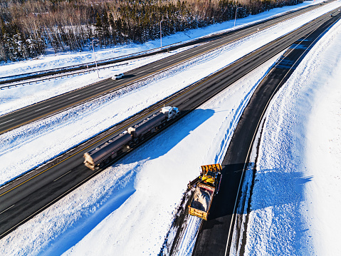A snowplow operator clears the edge of a highway on-ramp.