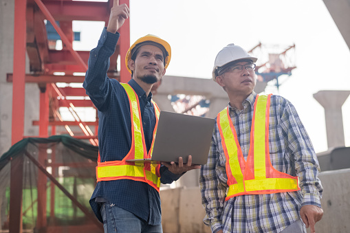 Construction Engineer using computer inspection on site highway road construction, Construction worker using laptop