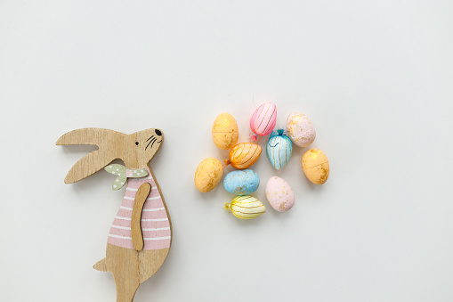 Easter toys. Wooden rabbit and wooden Easter eggs. White background, copy space.