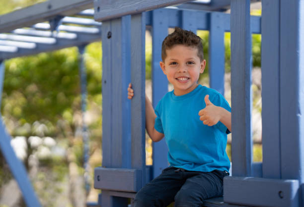 Menino sentado em cima de uma estrutura do playground - foto de acervo