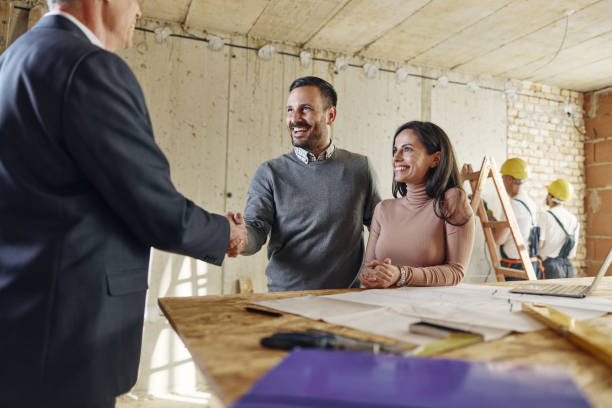 istock Happy couple came to an agreement with agent at construction site. 1471807152