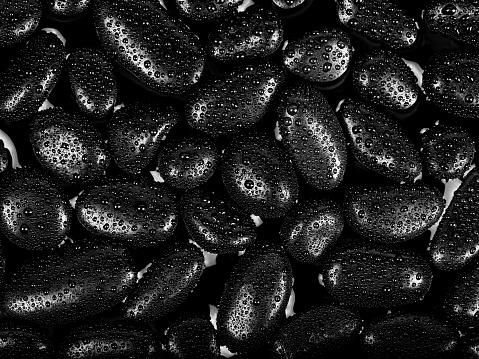 Black river stones texture and background. Black pebbles in water and water drop.