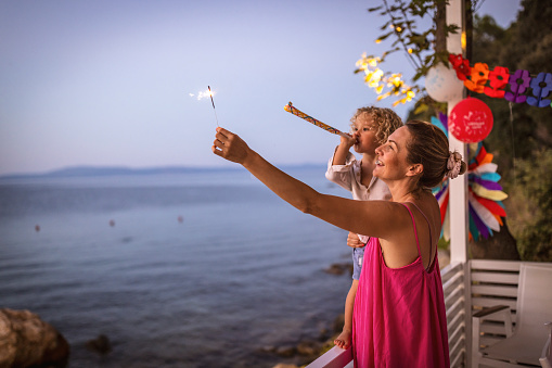 Photo of little boy and mother celebrating with sparkler fireworks birthday on a summer vacation