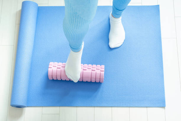istock Female leg rolls a massage foam roller close-up on blue mat, top view. 1471811911