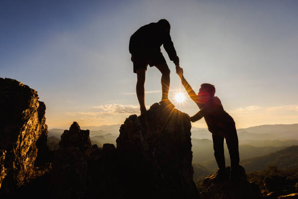 istock Silhouette of The men helping pull people up from high cliffs. 1471811928