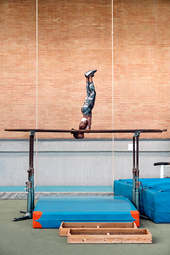 Stock photo of an African-American gymnastic woman practicing on parallel bars