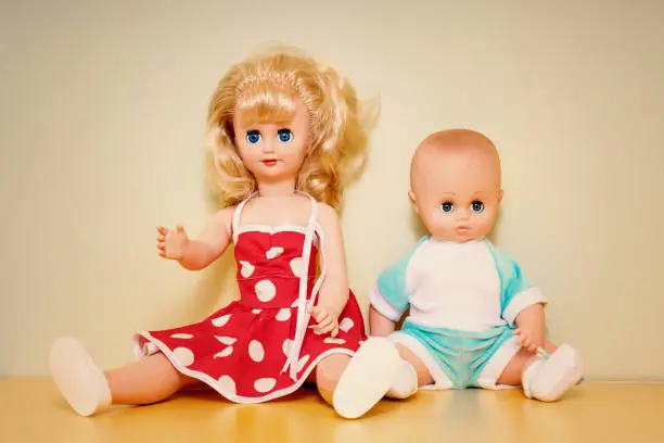 Photo of Couple of old retro plastic dolls seated on wooden table