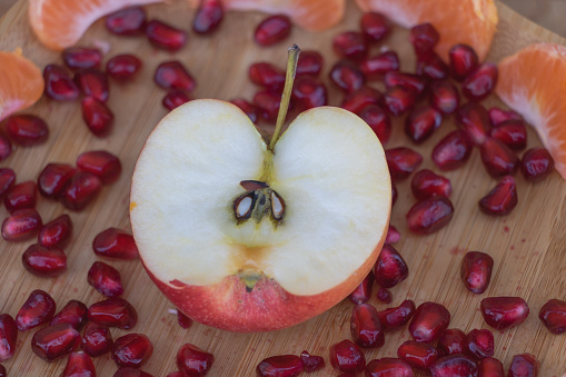 Apple and pomegranate on a wooden board, close up.