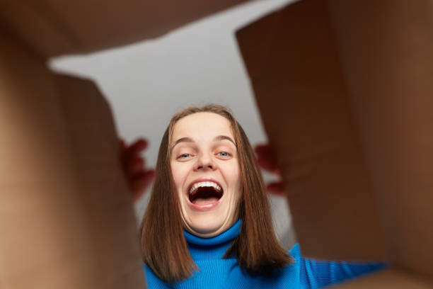 istock Extremely happy overjoyed woman customer wearing blue turtleneck opening parcel, looking inside package with cheerful joyful look, being glad to receive excellent present. 1471818465