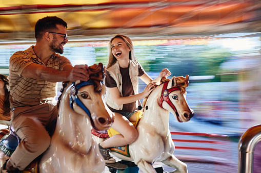 Carefree couple on merry-go-round carousel ride in blurred motion.