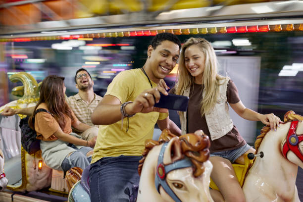 istock Happy couple taking a selfie during carousel ride at amusement park. 1471819820
