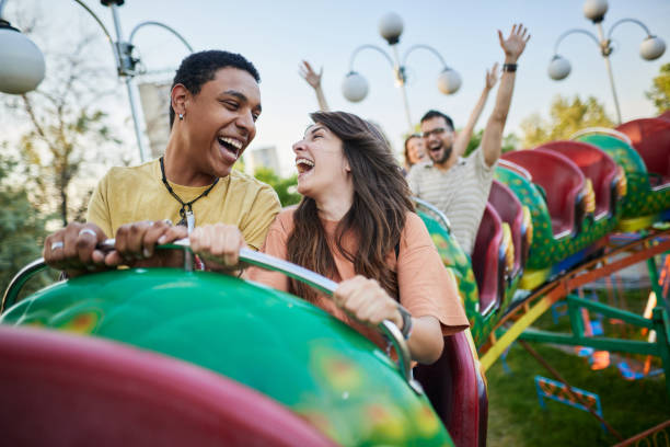 Young cheerful couple having fun on rollercoaster at amusement park.