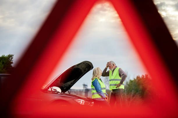 starsza para czuje się niezadowolona po awarii swojego samochodu na drodze. - warning triangle triangle car warning sign zdjęcia i obrazy z banku zdjęć