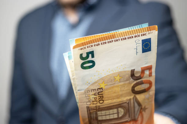 well dressed man holding in the hand or giving bunch of money, euro banknotes, european union paper currency - european union euro note european union currency paper currency currency imagens e fotografias de stock
