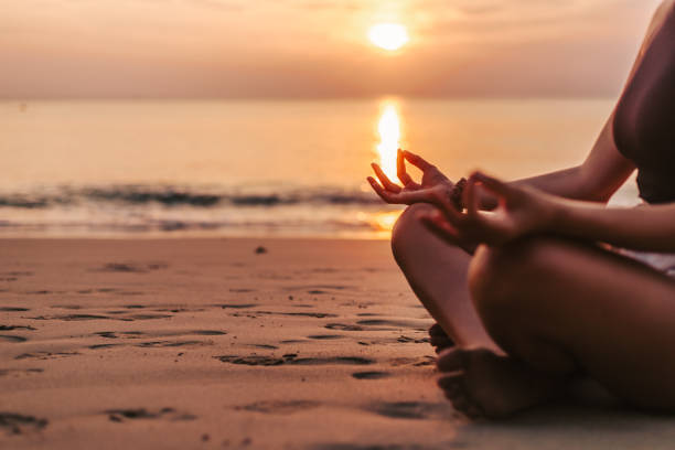 istock Woman meditating on the beach at sunset 1471822264