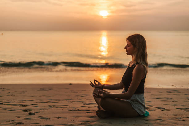 istock Woman meditating on the beach at sunset 1471822277