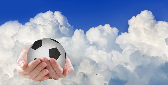 Image of a fantastic picture of the appearance of a soccer ball on the palms directly from the clouds