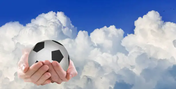 Image of a fantastic picture of the appearance of a soccer ball on the palms directly from the clouds