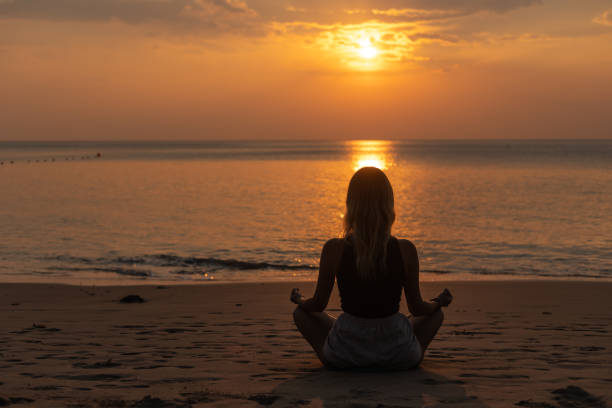 istock Woman meditating on the beach at sunset 1471823300