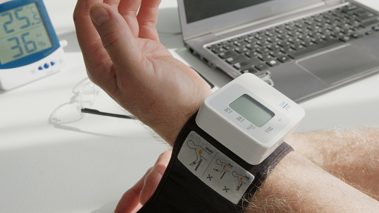 Man puts on a wristbandstyle tonometer to measure his blood pressure - close-up