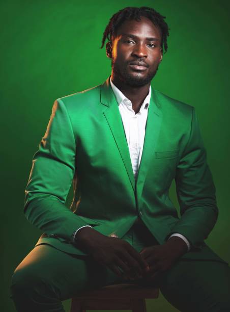 fashion, formal and black man in a green suit sitting on a chair in studio with a luxury outfit. elegant, stylish and portrait of an african male model with fashionable clothes isolated by background - anti smoking imagens e fotografias de stock