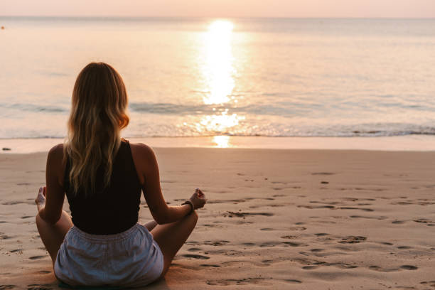 istock Woman meditating on the beach at sunset 1471824278
