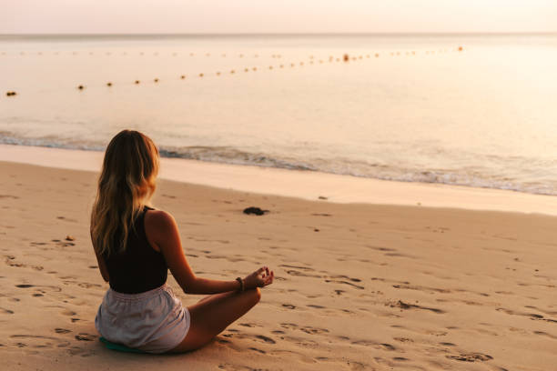 istock Woman meditating on the beach at sunset 1471826299