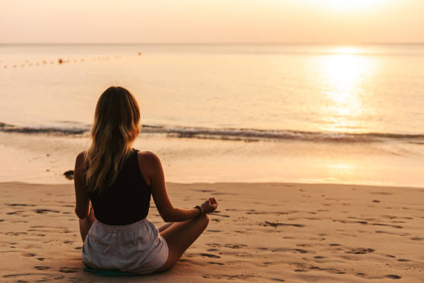 istock Young woman practicing yoga on the beach 1471827821