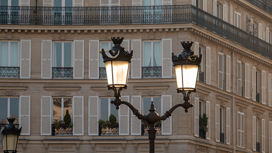 Characteristic Parisien architecture: detail of the facade of a building. Traditional lantern in the foreground (in the sunshine)