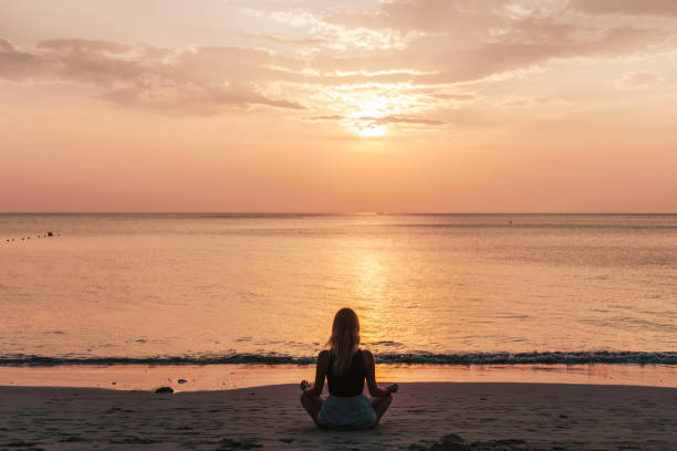 istock Young woman practicing yoga on the beach 1471829446