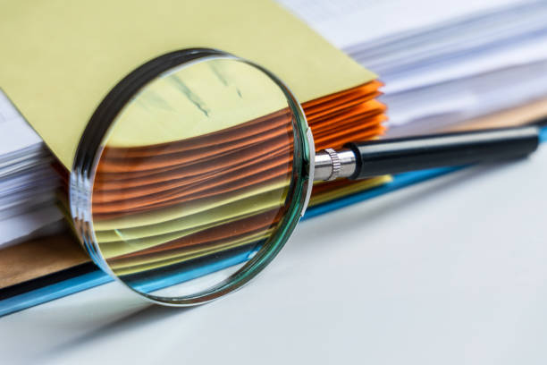 istock Magnifying glass in front of open office folder 1471832164