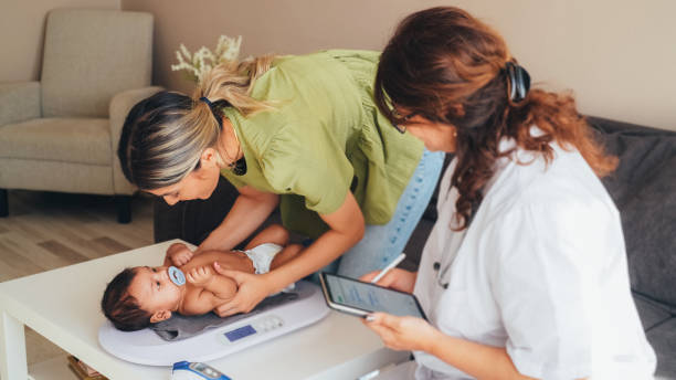 Doctor visiting young mother at home for routine checkup of the newborn stock photo
