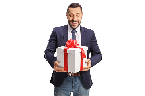 Happy young man in suit and tie holding a present box with red ribbon isolated on white background