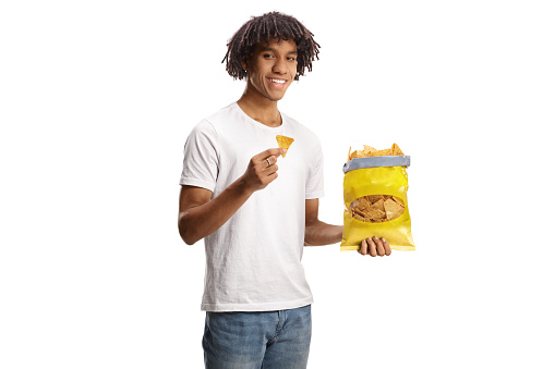 Young african american man eating tortilla crisps and smiling isolated on white background