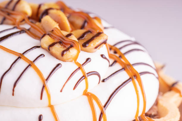 Delicious cupcakes with cream, caramel and nuts, on white background, macro shot