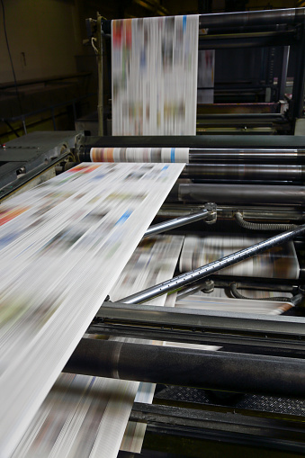 Printing press machine printing broadsheet newspapers in a printing plant.