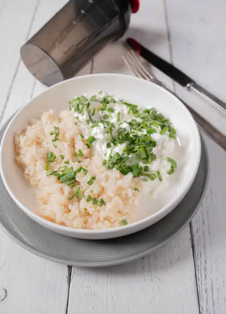Homemade healthy fitness dinner or lunch with cooked brown rice, cottage cheese and chives. Low fat and high protein meal. Served ready to eat on a plate on white background