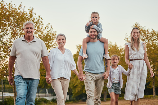 Nature, portrait and big family on a walk in the park for fresh air, exercise and adventure. Grandparents, parents and children walking together and holding hands in an outdoor garden in Australia.