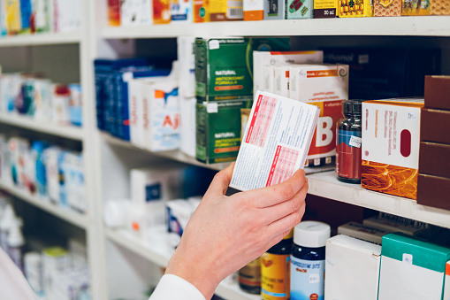 Una joven farmacéutica arregla los medicamentos en los estantes de la farmacia photo