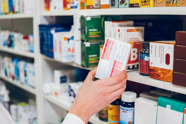 une jeune pharmacienne dispose des médicaments sur les étagères de la pharmacie - pharmacie photos et images de collection