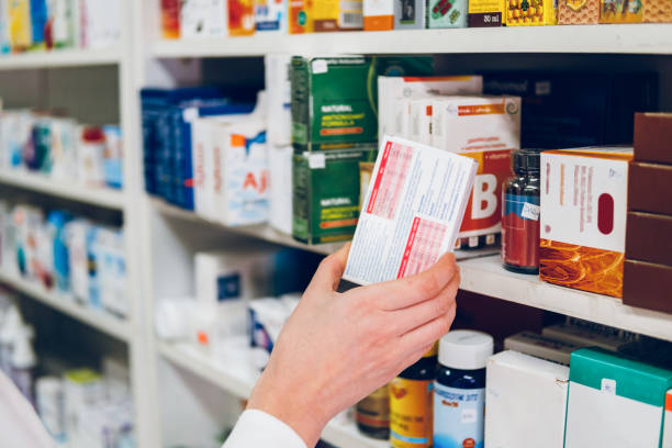 A young woman pharmacist arranges medicines on the shelves of the pharmacy A young female pharmacist arranges medicines on the shelves of the pharmacy and makes an inventory. drugs stock pictures, royalty-free photos & images