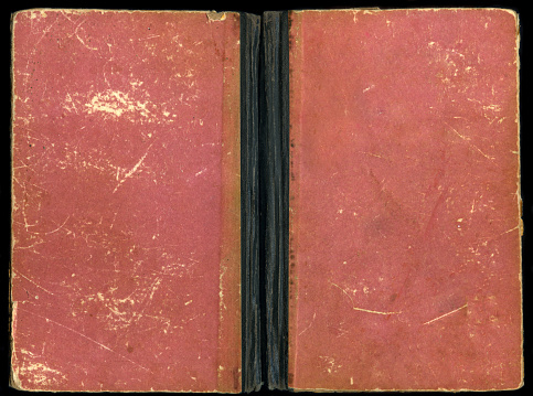 Cover of an old red book on a black background. The book is unfolded. Side view.