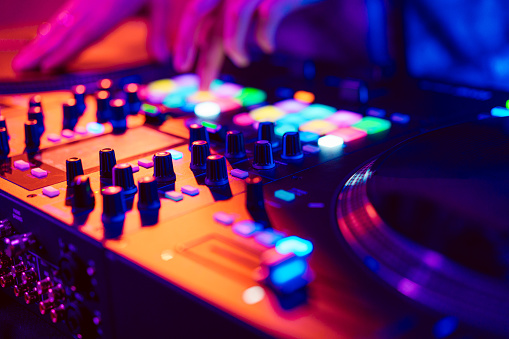 Close up of DJ hands on dj console mixer during concert in the night club