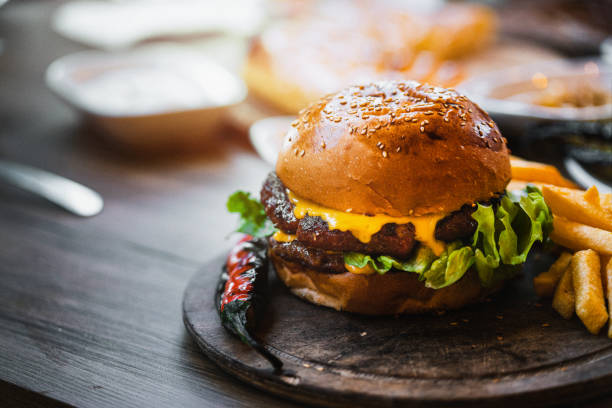 deliciosa hamburguesa doble con patatas fritas y verduras en tabla de cortar de madera - sandwich turkey gourmet fast food fotografías e imágenes de stock