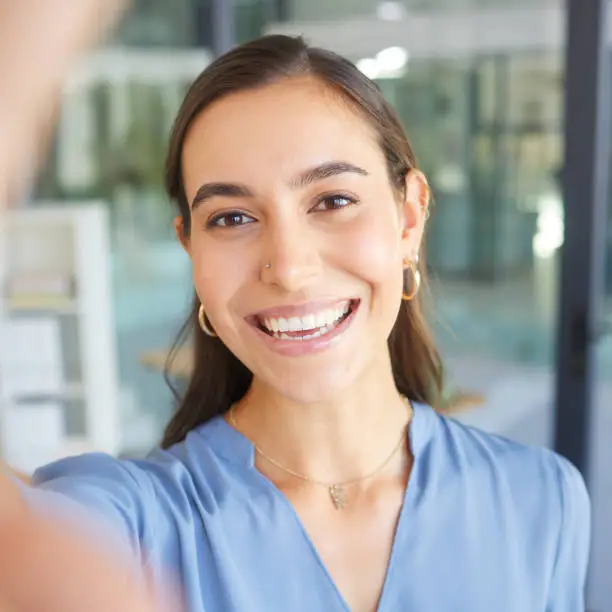 Photo of Happy, portrait or business woman taking a selfie in office building for a social media profile picture and smiles with pride. Face, photo or manager with goals, success mindset or motivation to work