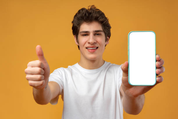 istock Smiling young man showing mobile phone blank white screen mockup to camera. 1471845465