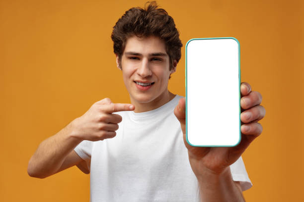 istock Smiling young man showing mobile phone blank white screen mockup to camera. 1471845805