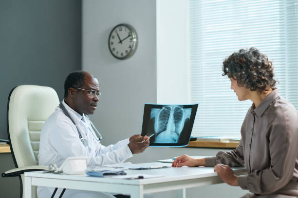 istock Mature doctor pointing at lung x-ray result while explaining it to patient 1471849267