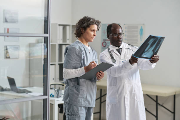 istock Mature female assistant with medical document looking at lung x-ray 1471849352