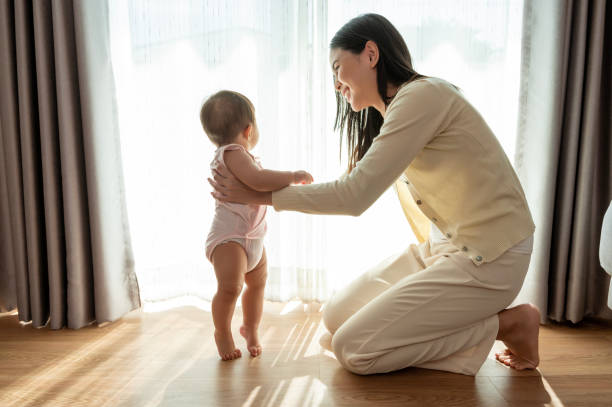 una bambina che impara i primi passi cammina con il concetto di madre, famiglia, bambino, infanzia e genitorialità - steps baby standing walking foto e immagini stock